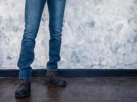 Close up of Man's legs in jeans and boots on wooden floor. Free space for text photo