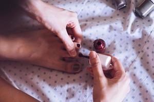 Close up of woman varnishing her toenails in the bedroom. Vintage tone photo