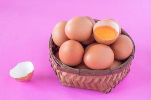 Eggs in wooden basket on a pink background. photo