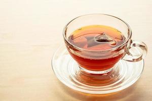 una taza de té en la mesa de madera, bolsita de té en vidrio. foto