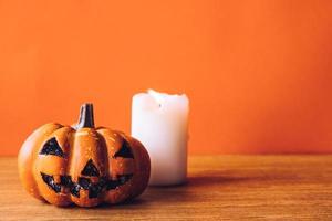 Halloween pumpkin with candlelight on an orange color background. Free space for text photo