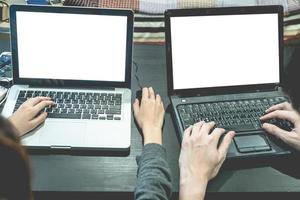 Business partners working together on the same desk, they are using a laptop with blank screen, Start up business concept photo