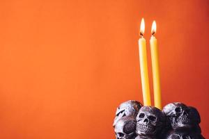 Skulls with candle burning on an orange color background. Free space for text photo