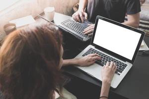 Coworkers working on the same desk, they are using a laptop with blank screen, Start up business concept photo