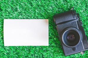 Top view of camera with blank photograph on green grass background. photo