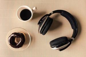 vista superior de los auriculares con taza de café y donut en la mesa. foto