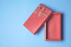 Top view of open red gift box on blue background. Free space for text photo