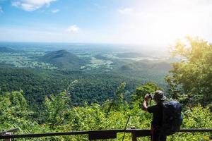 Man traveler taking picture on top of mountain with blue sky. photo