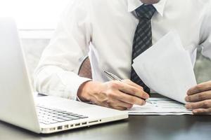 Close up of Businessman checking document on the desk. photo