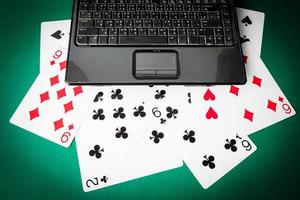 Laptop with playing cards on green background. photo