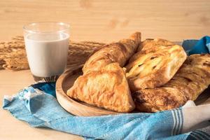 Assortment of pastries with milk on wooden table background. photo