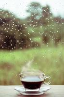 Cup of coffee on the table inside the window, coffee break in the morning with rainy day, relaxing and refreshing concepts. photo