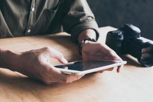 el primer plano del fotógrafo sube imágenes desde la cámara a la tableta. foto