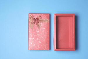 Top view of open red gift box on blue background. Free space for text photo