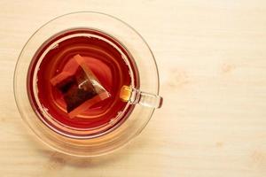 una taza de té en la mesa de madera, bolsita de té en vidrio. foto