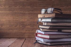 viejos libros de tapa dura con gafas sobre una mesa de madera. espacio libre para texto. foto