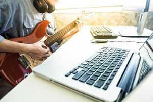 músico profesional grabando guitarra eléctrica en estudio digital en casa, concepto de tecnología de producción musical foto