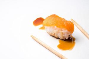 Sushi, japanese food, rice with salmon, chopsticks and sauce on white background. photo