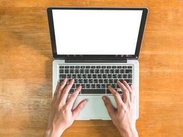 Top view of Male hands using Laptop with blank screen on wooden table photo