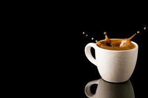 Cup of splashing coffee on black background. Free space for text photo