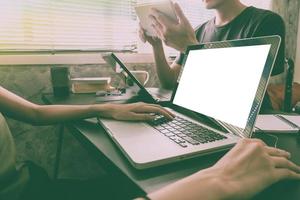 Coworkers working on the same desk, they are using a laptop with blank screen, Start up business concept, Vintage tone photo