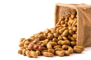 Peanuts in burlap bag on white background. photo