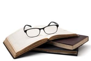 A stack of old books with eyeglasses on a white background. photo