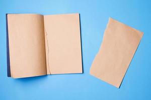 Blank notebook with a piece of note paper on blue background. photo