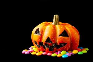 Halloween pumpkin with candies on a black background. photo