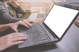 Business partners working together on the same desk, they are using a laptop with blank screen, Start up business concept photo