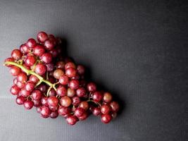 vista superior de uvas rojas sobre un fondo negro. espacio libre para texto foto