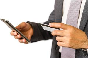 Close up of businessman holding credit card and using smart phone isolated on white background. photo