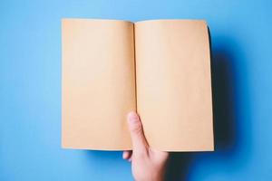 Top view of hands holding a blank book ready with copy space ready for text on blue background. photo