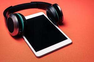 Modern headphones with tablet pc on a orange background. photo