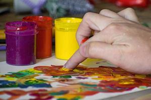 Hand of a girl mixing colors with fingers for painting. Abstract painting with gouache. Finger paint photo