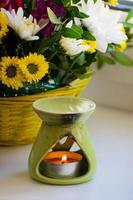 Oil burner with chrysanthemums by the side. Aromatherapy burner. Oil, aromatherapy burner, flowers and candles for spa and relaxation. photo