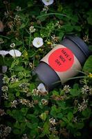 Brown paper glass with black lid for coffee on green grass. Cup of coffee on the grass. photo