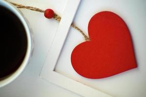 taza de amor, café con corazón rojo. corazón rojo en una cuerda en el marco de madera. día de San Valentín. Mañana. el 14 de febrero. foto