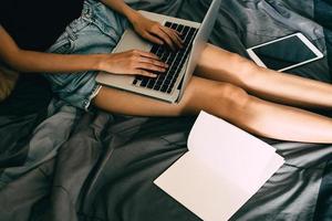 Close up of young woman using laptop in bed,  Films grain filter. photo