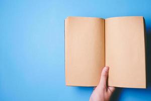 Top view of hands holding a blank book ready with copy space ready for text on blue background. photo