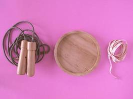 Skipping rope, empty dish and tape measure on a pink background. photo