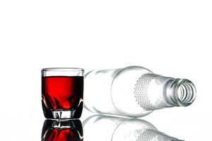 Glass of alcohol and empty bottle on a white background. photo