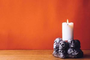 Skulls with a candle burning on an orange color background. Free space for text photo