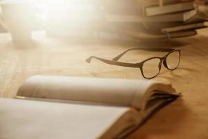 Close up of eyeglasses with books on wooden desk, Selective focus,  Flare sun light,Vintage tone. photo