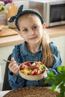 Cute little girl eats fruit salad photo