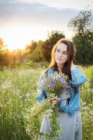 hermosa chica caminando en el campo en verano con flores silvestres. foto