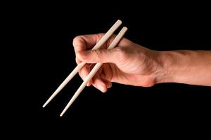 Hand holding chopsticks on black background. photo