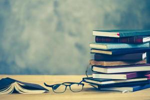 Stack of books with eyeglasses on the wooden table, Free space for text, Vintage tone. photo