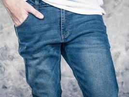 Close up of Man's legs in jeans on gray grunge background. photo