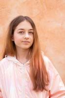 A teenage girl in a pink jacket on a beige background. Portrait of a beautiful girl. photo